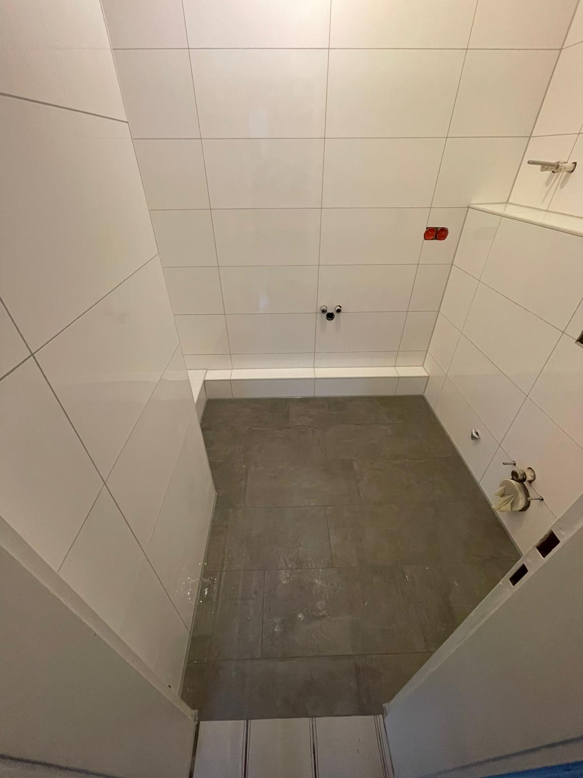 G&auml;ste-WC mit weissen Wandfliesen und grauem Boden