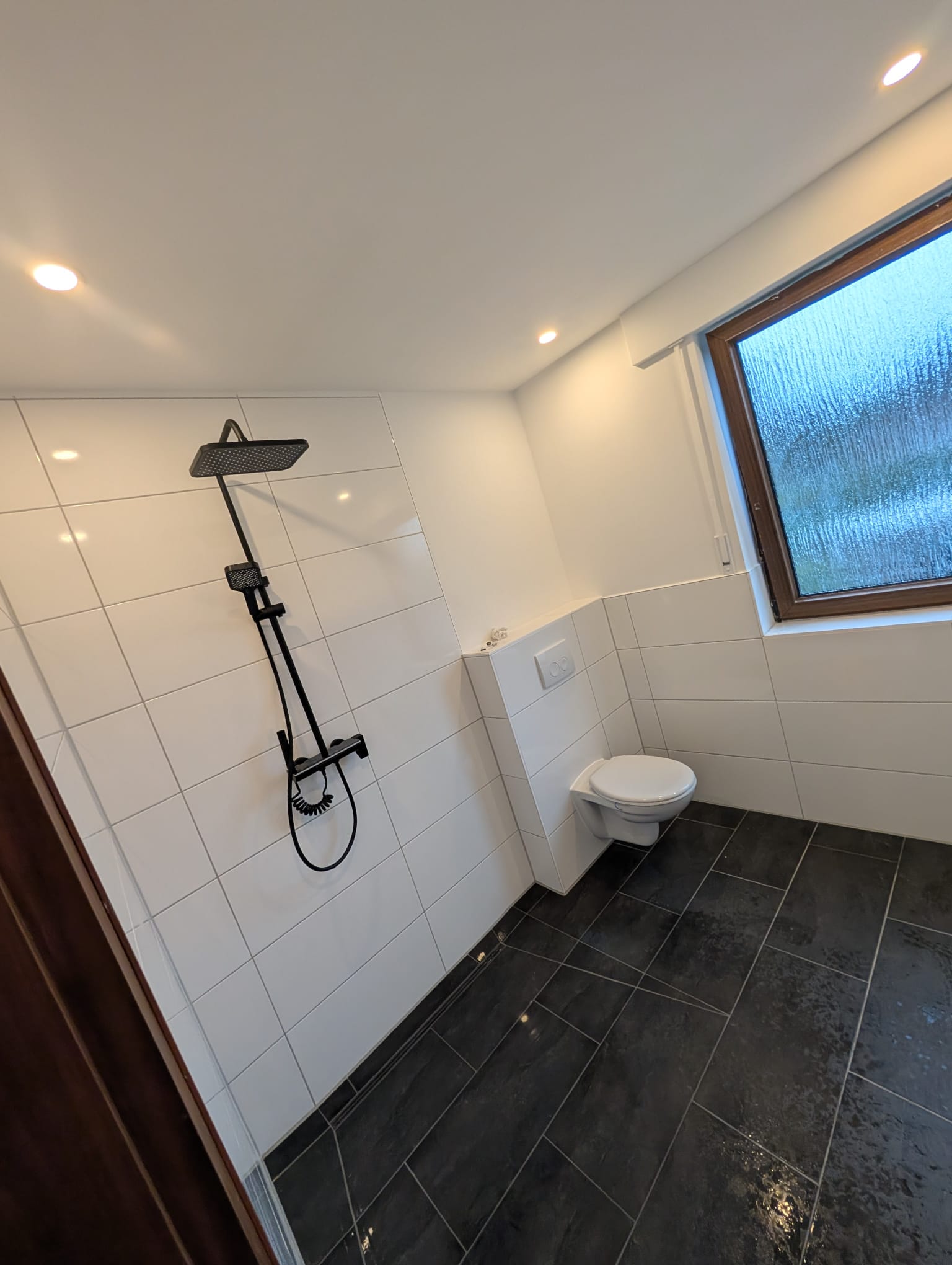 Modernes Badezimmer mit schwarzer Regendusche und anthrazitfarbenem Boden