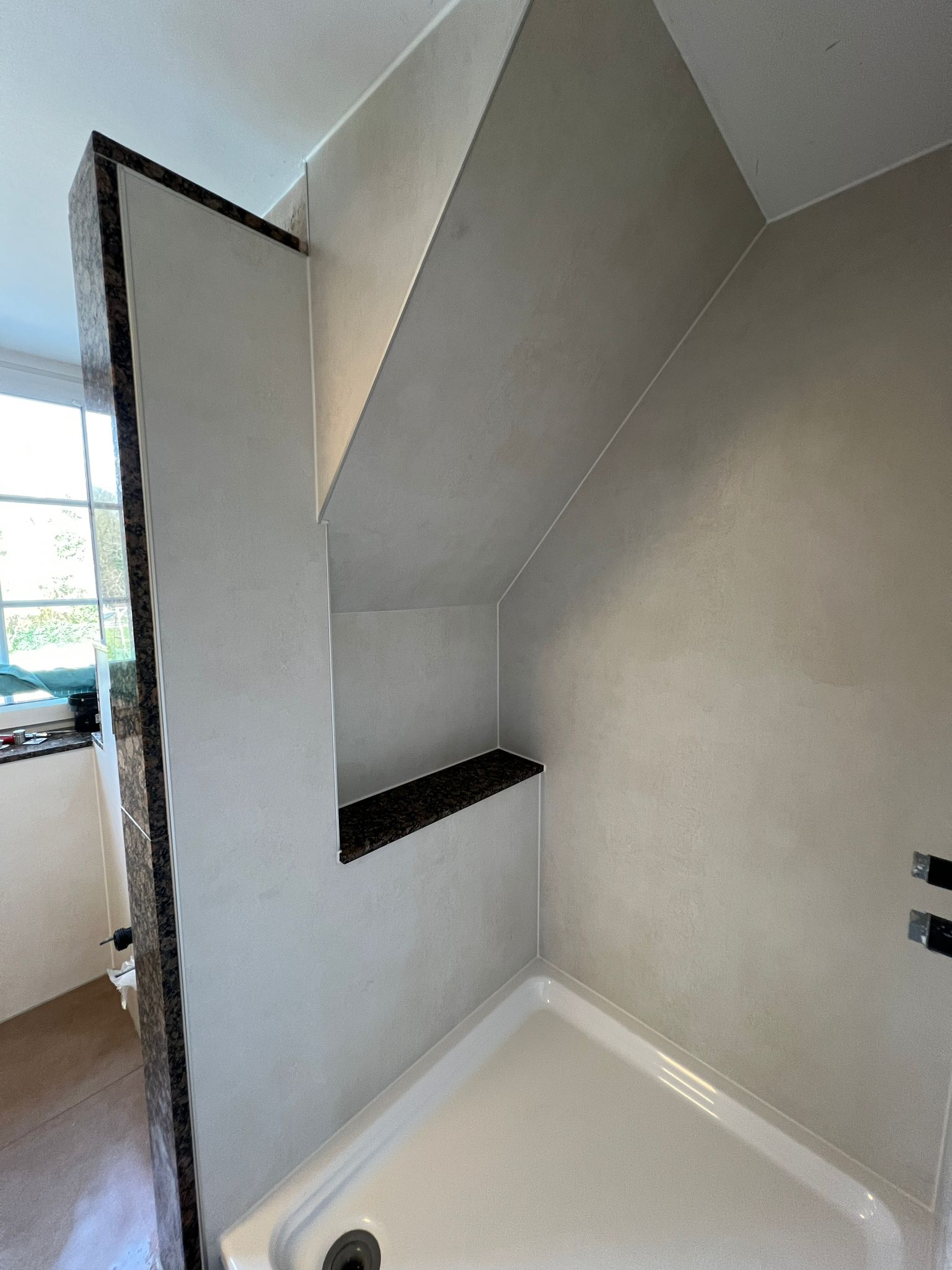 Walk-in-Dusche in Betonoptik mit dunkler Granitablage